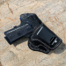 Black leather IWB holster with 10 degree cant and metal belt clip on stone surface