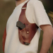 Brown leather sling shoulder holster worn over white shirt with 1911-style pistol