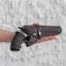 Brown leather belt revolver holster in hand with partially inserted revolver and retention strap