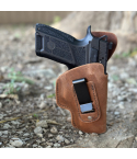 Brown leather IWB holster with clip holding compact pistol in outdoor setting