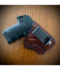 Brown leather IWB holster with zero cant and metal belt clip on wooden surface