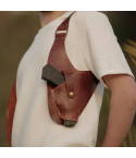 Brown leather sling shoulder holster worn over white shirt with 1911-style pistol
